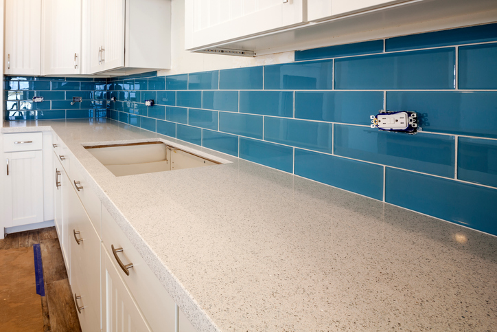 A detailed view of new construction of a kitchen counter with glass tile backsplash.